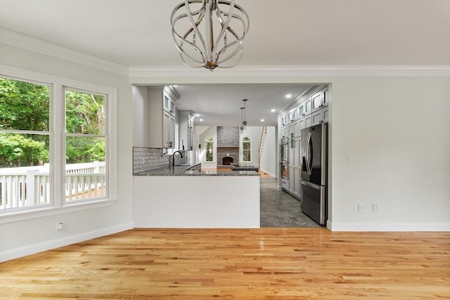 453 Forest St, North Andover, MA 01845 - kitchen with stainless steel refrigerator with ice dispenser, a chandelier, a large fireplace, glass insert cabinets, and light wood-type flooring