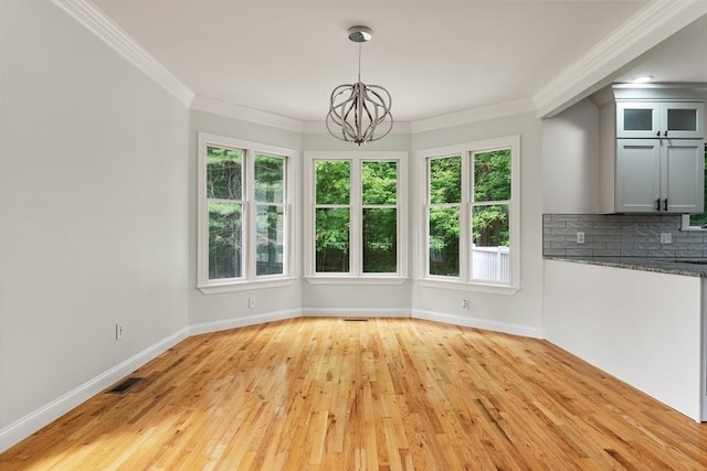 453 Forest St, North Andover, MA 01845 - unfurnished dining area with a chandelier, plenty of natural light, light wood finished floors, and crown molding