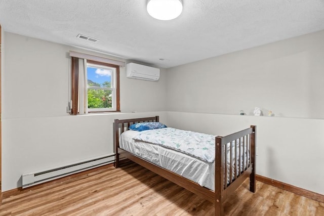 46 Lisa Ln, Methuen, MA 01844 - bedroom with an AC wall unit, wood finished floors, a baseboard radiator, and a textured ceiling