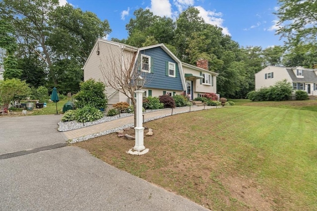 46 Lisa Ln, Methuen, MA 01844 - view of front of home with asphalt driveway, a front lawn, a chimney, and view of scattered trees