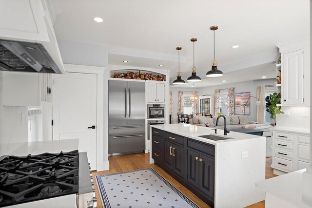 38 Thatcher St, Medford, MA 02155 - kitchen featuring appliances with stainless steel finishes, a sink, a center island with sink, white cabinets, and under cabinet range hood
