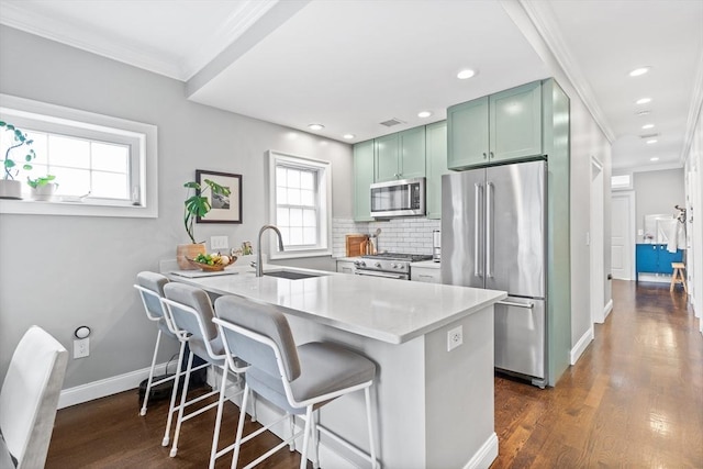 kitchen featuring a sink, high quality appliances, a healthy amount of sunlight, and green cabinets