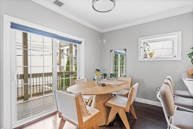 dining room featuring crown molding, baseboards, visible vents, and wood finished floors