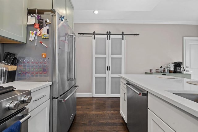 kitchen with ornamental molding, a barn door, dark wood-type flooring, light countertops, and appliances with stainless steel finishes