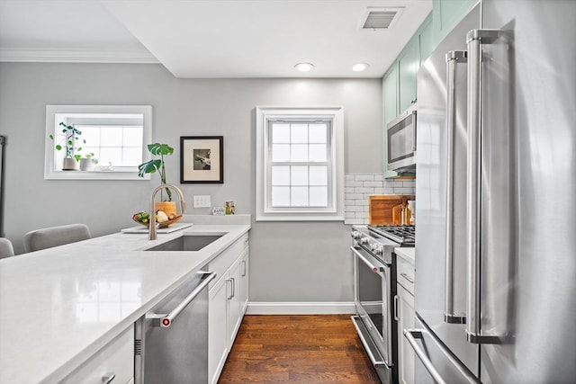 kitchen featuring a sink, high end appliances, visible vents, dark wood-style flooring, and light countertops