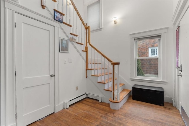 stairs featuring a baseboard heating unit and wood finished floors