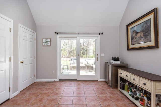 doorway with vaulted ceiling, baseboards, and light tile patterned floors