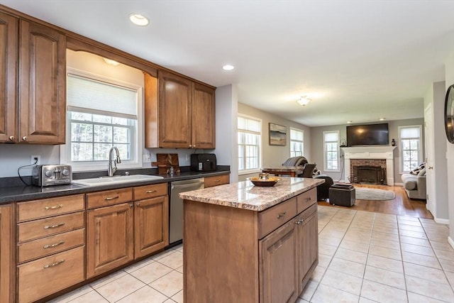 kitchen with a center island, stainless steel dishwasher, a healthy amount of sunlight, and a sink