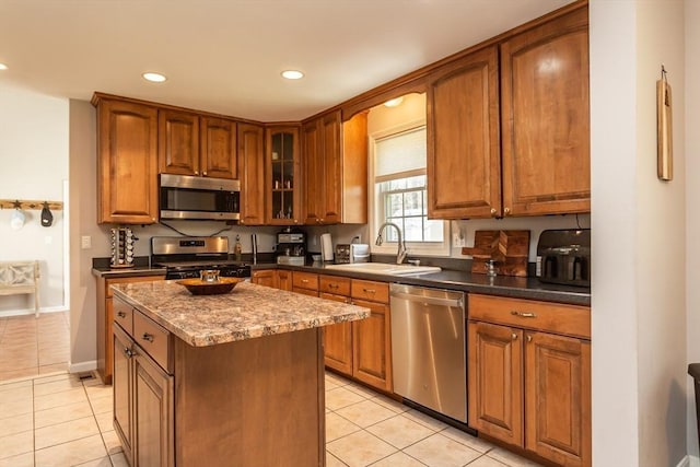 kitchen featuring stainless steel appliances, a sink, brown cabinetry, and light tile patterned floors