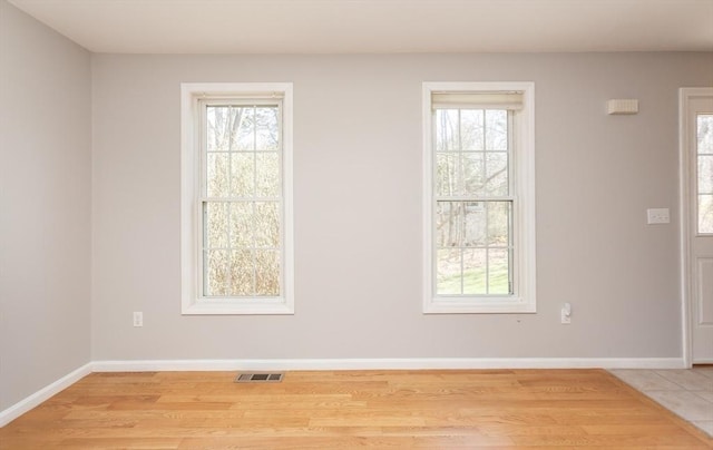 unfurnished room featuring light wood-style flooring, visible vents, and plenty of natural light