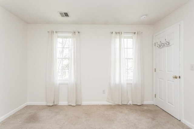 empty room with light carpet, visible vents, and a healthy amount of sunlight