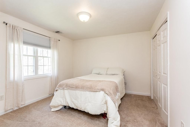 bedroom featuring baseboards, a closet, visible vents, and carpet