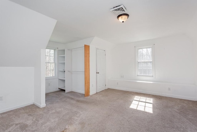 unfurnished bedroom featuring carpet floors, multiple windows, visible vents, and baseboards