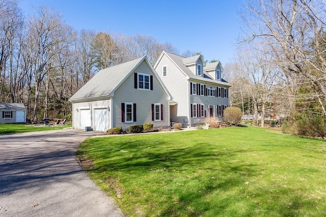 view of front of property featuring a shed, driveway, an outdoor structure, a front yard, and a garage