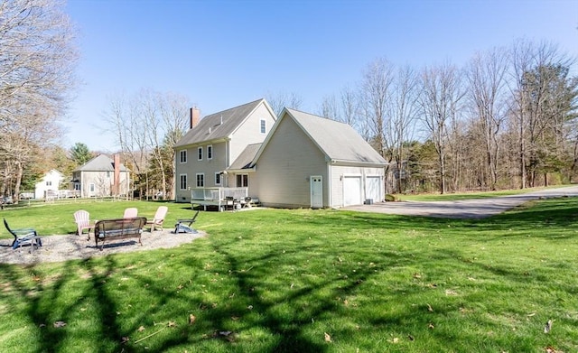 rear view of house featuring a garage, a yard, and a wooden deck