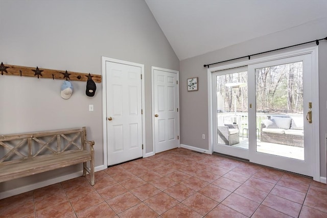 doorway featuring high vaulted ceiling, baseboards, and light tile patterned flooring