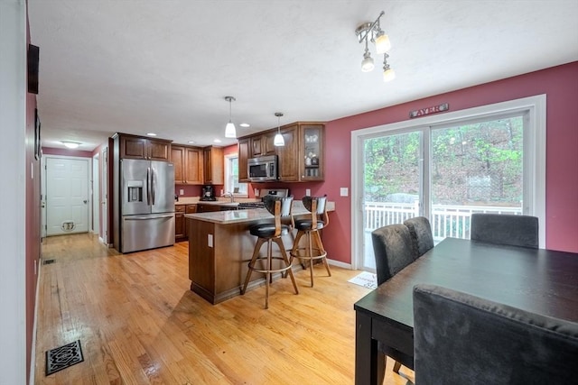 36 Westford Rd, Ayer, MA 01432 - kitchen with stainless steel appliances, a peninsula, light wood-type flooring, glass insert cabinets, and a breakfast bar