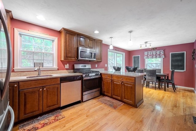 36 Westford Rd, Ayer, MA 01432 - kitchen featuring stainless steel appliances, a sink, a peninsula, light countertops, and light wood-type flooring