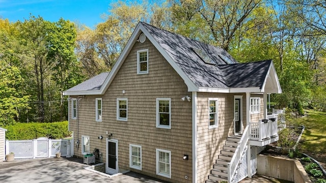 view of home's exterior featuring a shingled roof, stairs, and a patio area