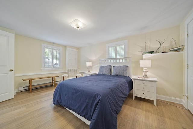 bedroom with a baseboard radiator, light wood finished floors, and baseboards