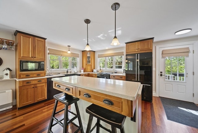 kitchen featuring black appliances, a sink, dark wood finished floors, and brown cabinets