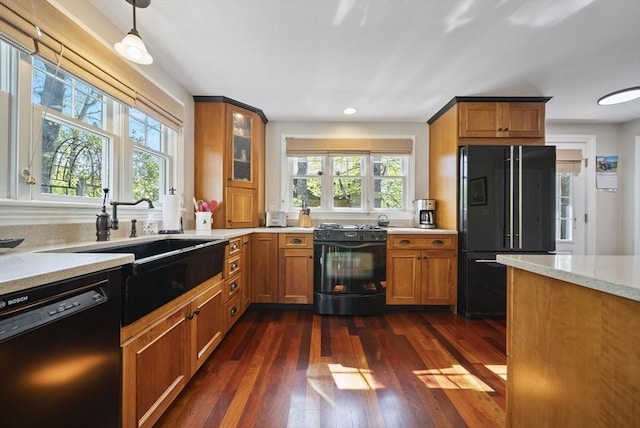 kitchen featuring black appliances, brown cabinetry, dark wood finished floors, glass insert cabinets, and recessed lighting
