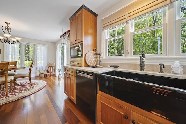 kitchen with black appliances, brown cabinets, a sink, light countertops, and dark wood finished floors