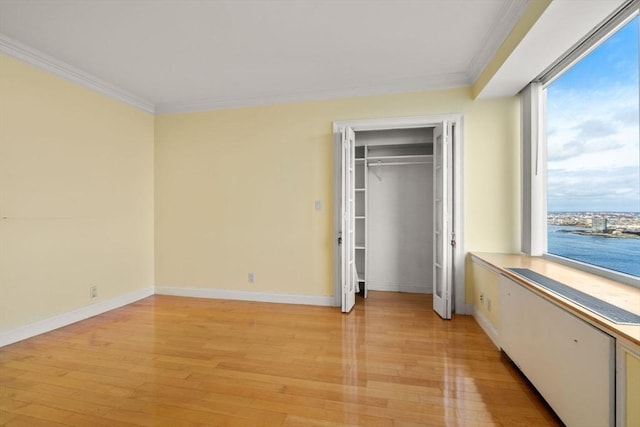 unfurnished bedroom with baseboards, crown molding, and light wood finished floors