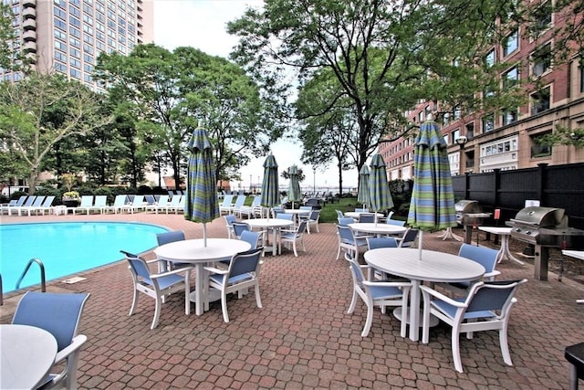 pool featuring a patio area, area for grilling, and fence