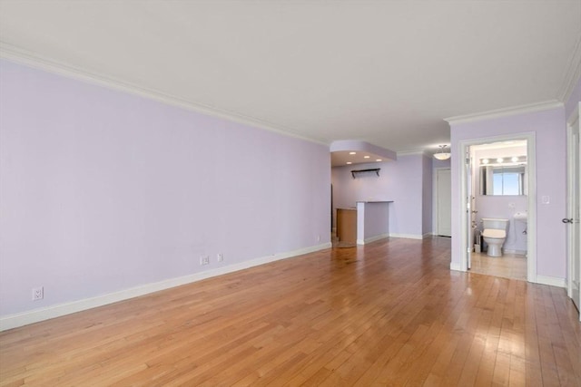 unfurnished living room featuring baseboards, light wood-style floors, and crown molding