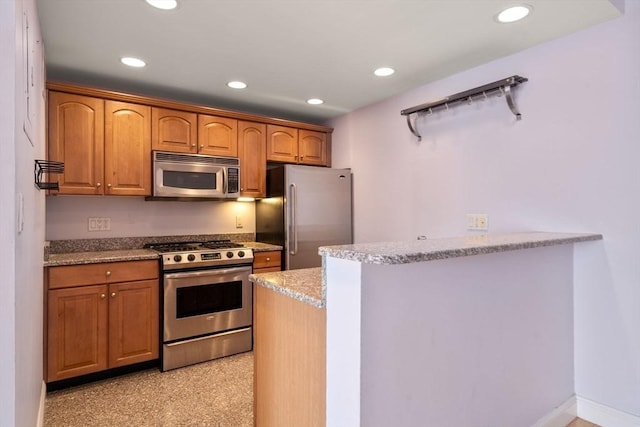 kitchen featuring a peninsula, light stone counters, recessed lighting, and appliances with stainless steel finishes