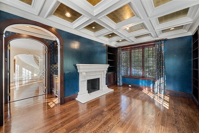 unfurnished living room featuring a fireplace with raised hearth, wood finished floors, beam ceiling, and built in features