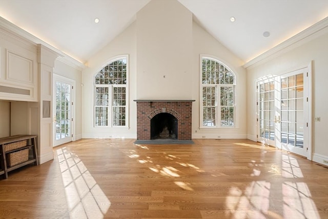 living area featuring a brick fireplace, baseboards, high vaulted ceiling, and light wood finished floors