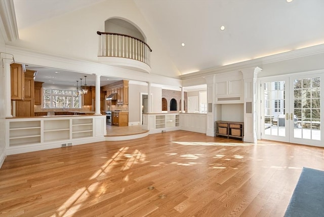 unfurnished living room featuring visible vents, light wood-style flooring, ornamental molding, french doors, and high vaulted ceiling