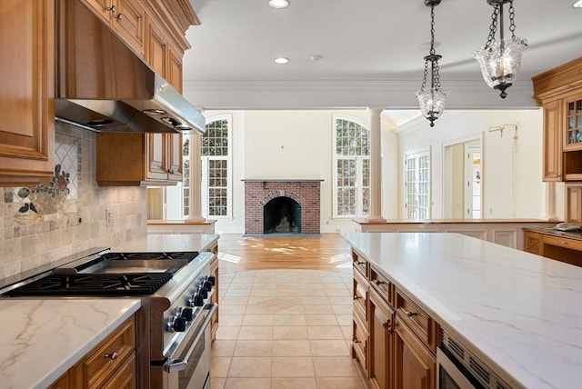 kitchen with appliances with stainless steel finishes, hanging light fixtures, crown molding, under cabinet range hood, and light tile patterned flooring