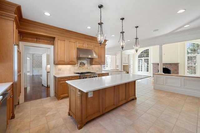 kitchen featuring ornamental molding, a center island, decorative light fixtures, and under cabinet range hood