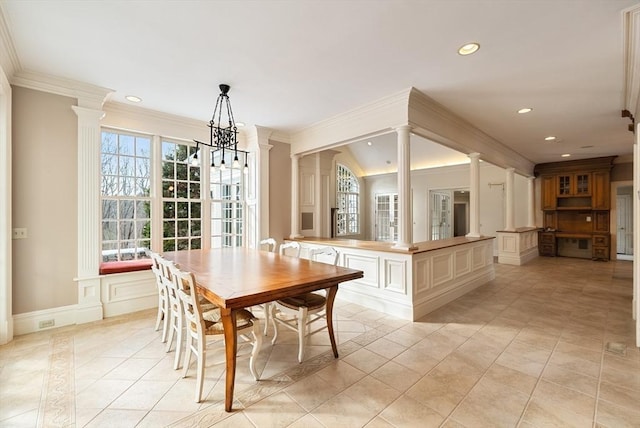 dining area featuring light tile patterned floors, decorative columns, ornamental molding, and a decorative wall