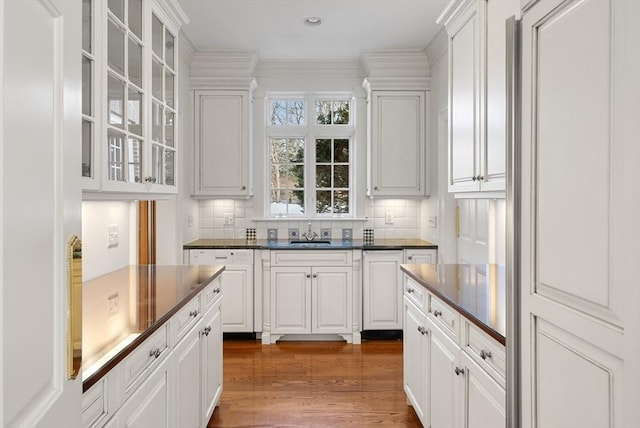 kitchen featuring glass insert cabinets, dark countertops, and white cabinetry