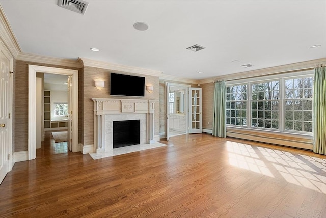 unfurnished living room featuring a high end fireplace, visible vents, and wood finished floors