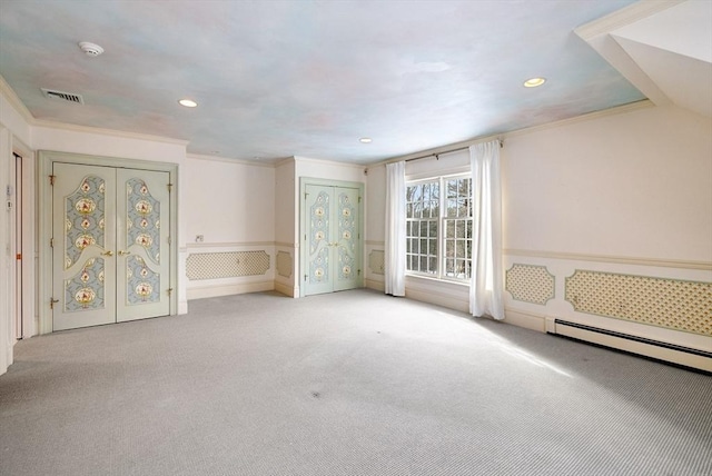 unfurnished room with a baseboard heating unit, wainscoting, visible vents, and crown molding