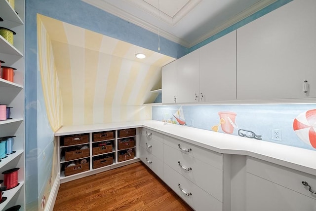 interior space featuring white cabinets, light countertops, crown molding, and wood finished floors