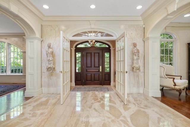 entryway featuring marble finish floor, ornamental molding, and a healthy amount of sunlight