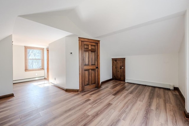 additional living space featuring a baseboard radiator, wood finished floors, and vaulted ceiling