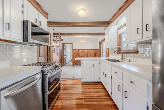 kitchen with a sink, stainless steel appliances, wainscoting, and light countertops