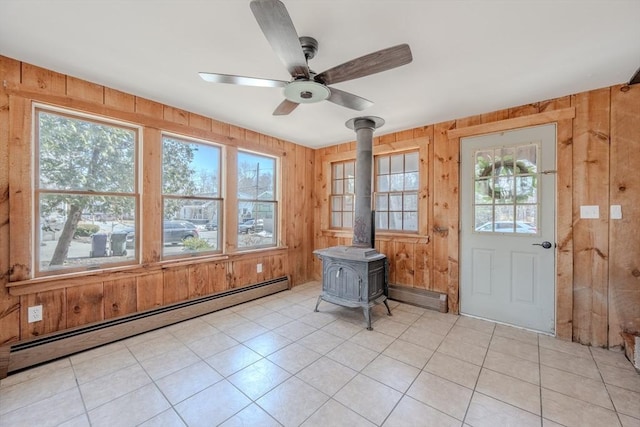 foyer entrance featuring a baseboard heating unit, wooden walls, a ceiling fan, and a wood stove