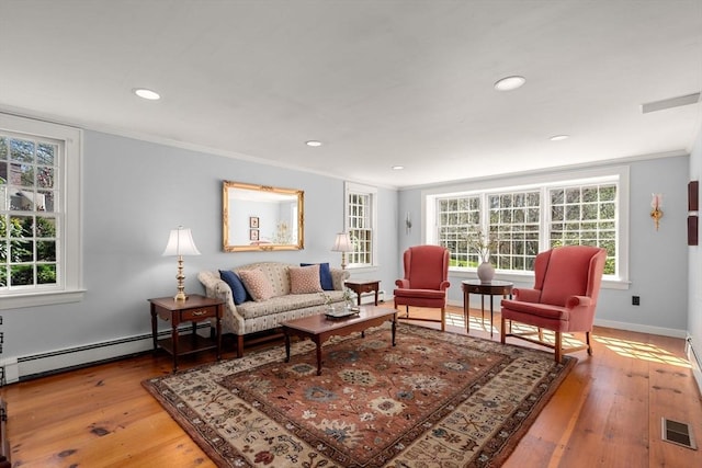 living area with ornamental molding, wood finished floors, and a healthy amount of sunlight