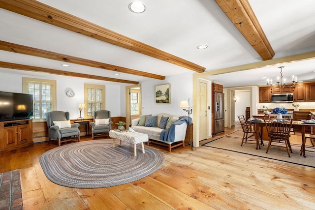 living area featuring beam ceiling, light wood-style floors, baseboard heating, recessed lighting, and a chandelier