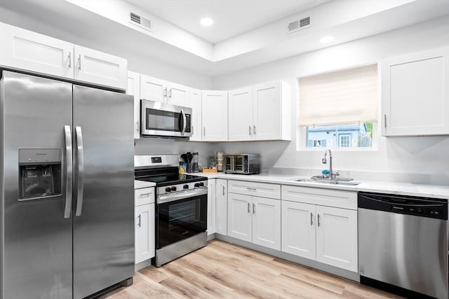50 Frankfort St Unit 1, Fitchburg, MA 01420 - kitchen with appliances with stainless steel finishes, a sink, light countertops, white cabinetry, and light wood-style floors