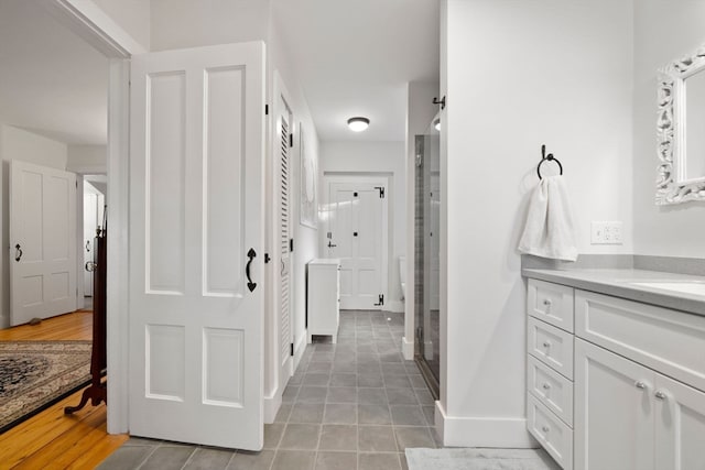 bathroom with vanity, a shower with shower door, and hardwood / wood-style flooring