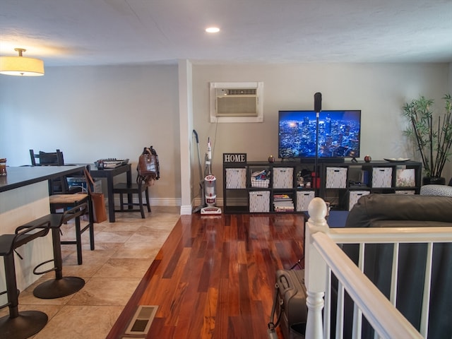 living room with a wall mounted air conditioner and hardwood / wood-style flooring